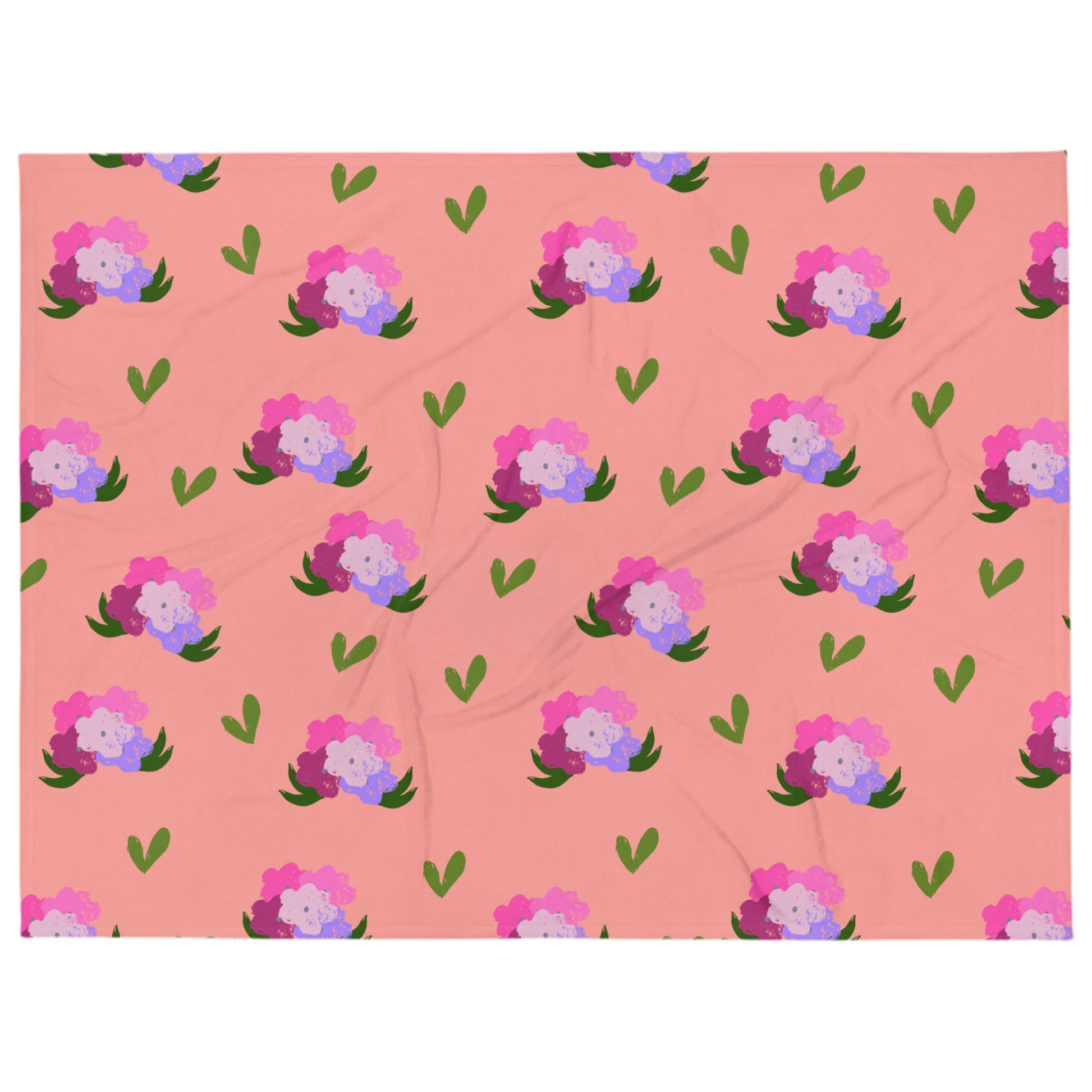 A photo of a soft pink blanket adorned with hand-drawn green leaves and bouquets of flowers in shades of pink and purple.