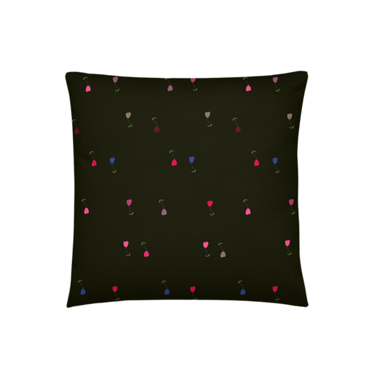 A photo of a dark pillow with colourful tulips on it (in shades of pink, grey, red, and blue with green leaves and green stalks). 