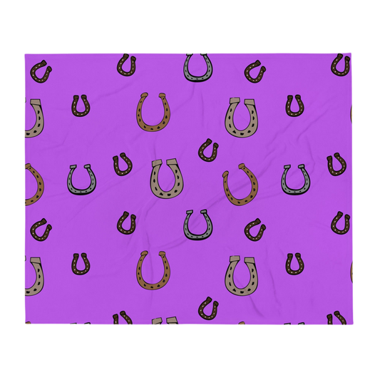 A photo of a vibrant purple blanket patterned with hand-drawn horseshoes in shades of grey and brown.