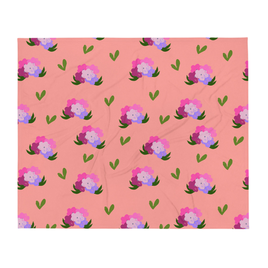 A photo of a soft pink blanket adorned with hand-drawn green leaves and bouquets of flowers in shades of pink and purple.