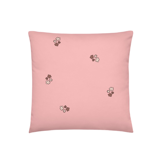 A photo of a pale pink pillow patterned with bunches of little flowers in neutral brown tones. 