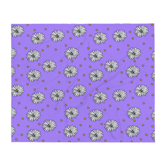 A photo of a purple blanket patterned with hand-drawn white daisies with yellow centres and miniature hand-drawn yellow flowers. 