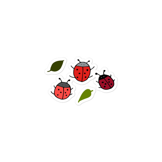 A photo of hand-drawn ladybug stickers in shades of red and hand-drawn leaf stickers in shades of green. 